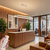 Lámpara ovalada blanca en recepción de oficina con acabados de madera y vidrio.