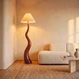Rincón de lectura minimalista con luminaria de pie de madera noble que genera un ambiente zen.