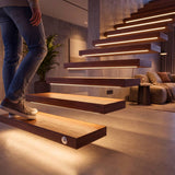 Escalera de madera con cintas LED encendidas al detectar el paso
