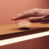 Mano pasando sobre sensor sin contacto que enciende cinta LED en repisa
