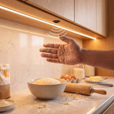 Mano con harina encendiendo cinta LED de cocina con sensor sin contacto