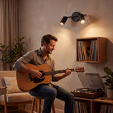 Spot doble iluminando a hombre tocando guitarra junto a su laptop