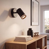 Spot negro como aplique dirigible iluminando la pared con cuadros