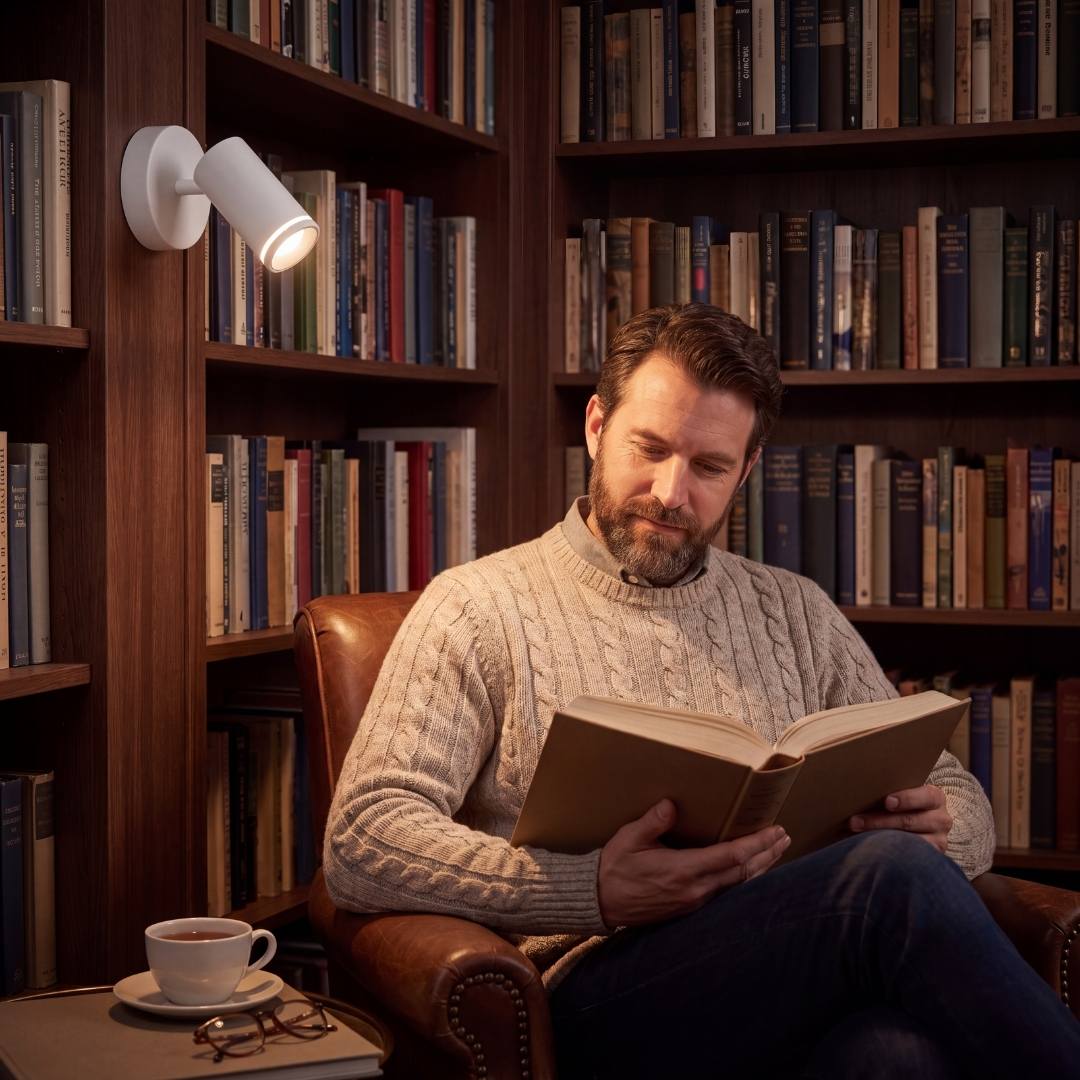 Spot de pared iluminando la lectura junto a la biblioteca