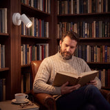 Spot de pared iluminando la lectura junto a la biblioteca