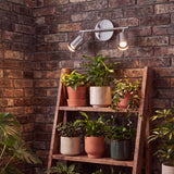 Spot cromado iluminando estante con plantas y luz cálida