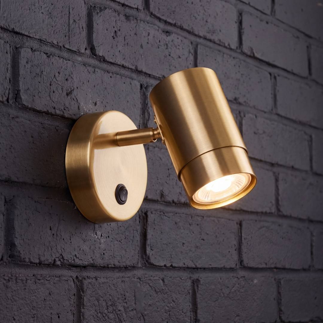 Spot dorado satinado con cabezal orientado sobre pared de ladrillo oscuro