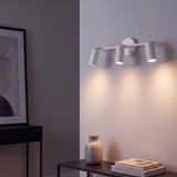Spot triple blanco como aplique proyectando luz en pared oscura
