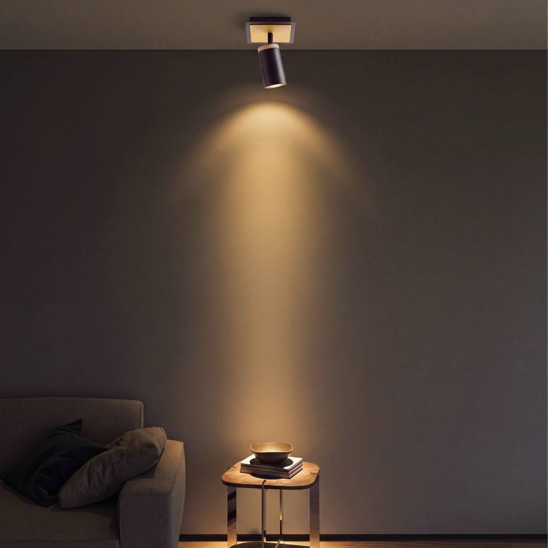 Spot de pared proyectando haz de luz cálida sobre mueble de noche