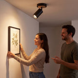 Pareja decorando la pared junto al spot dirigible que ilumina el cuadro