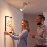 Pareja decorando la pared junto al spot dirigible que ilumina el cuadro