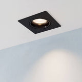 Spot empotrable cuadrado LEA negro encendido en techo blanco con luz cálida sobre muro celeste