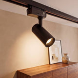 Spot LED para riel LEXI negro encendido iluminando un cuadro sobre consola