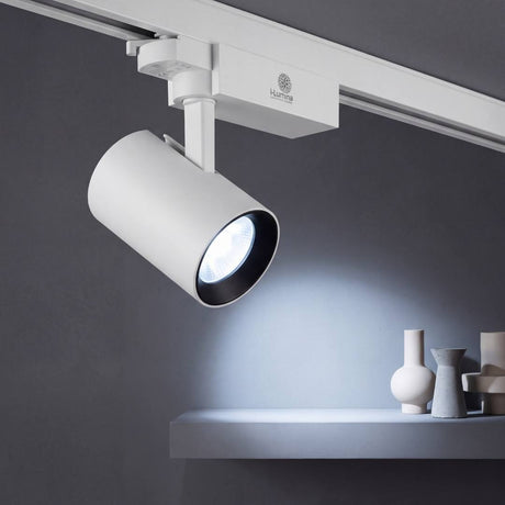 Spot LED para riel ROXY blanco 18W encendido con luz fría sobre repisa decorativa