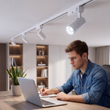 Hombre trabajando bajo spots LED de riel con luz fría en un home office