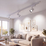 Riel con spots LED blancos iluminando una sala moderna con cuadros
