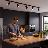 Hombre cocinando bajo spots LED negros de riel en una cocina moderna