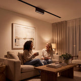 Spot LED de riel con cabezal articulado dirigiendo luz cálida en sala
