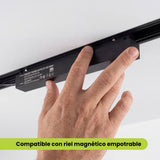 Mano inserta el transformador magnético dentro del riel empotrable en el techo