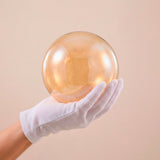 Close-up de esfera de cristal ámbar artesanal resaltando el acabado traslúcido.